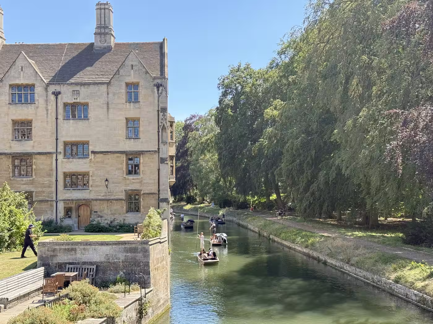 A honey-stone Cambridge college beside the River Cam with punts